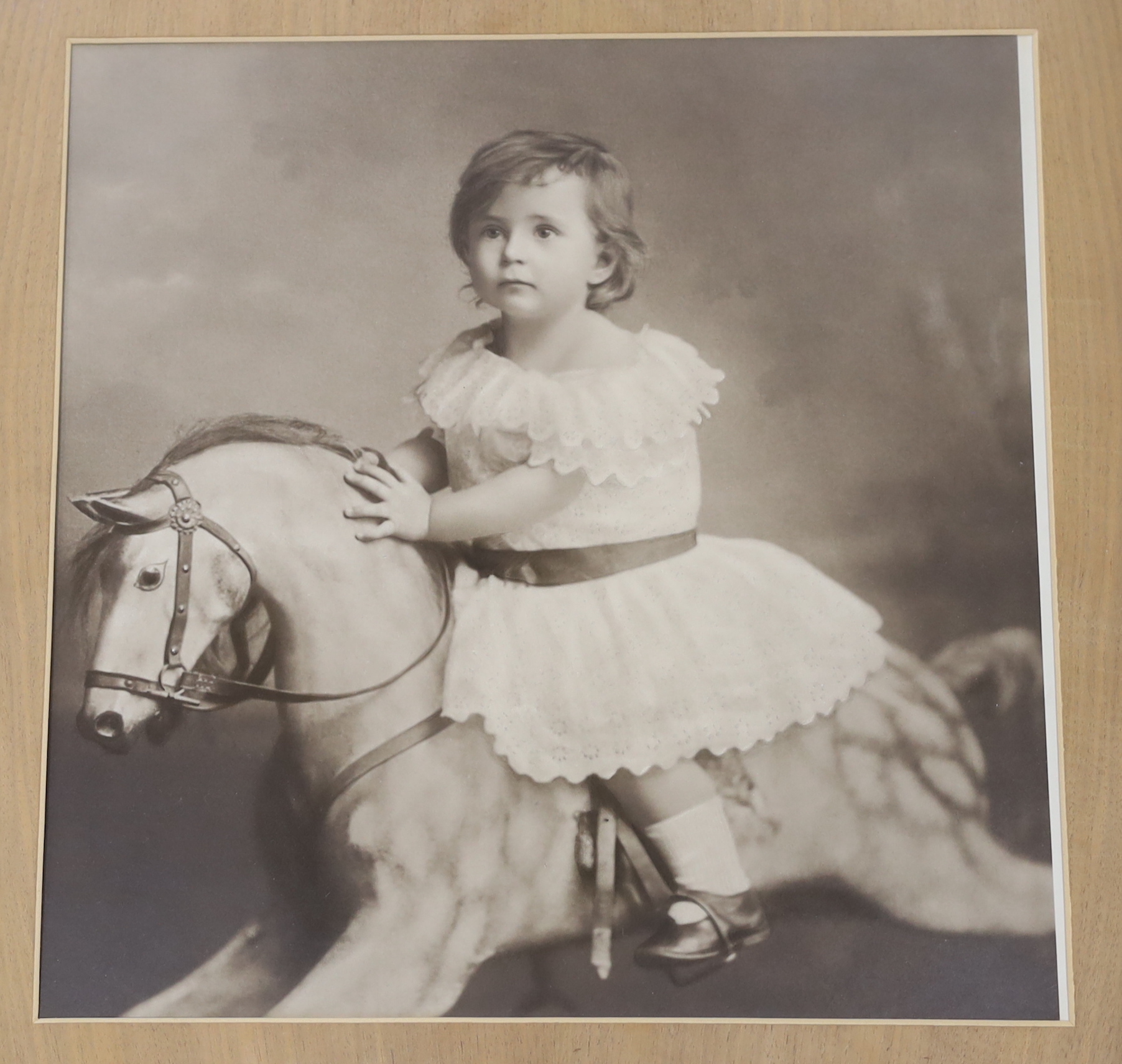 A large photographic print, Infant on rocking horse, housed in a carved frame ‘Russel, 1891’, and another similar framed sepia photograph, largest overall 79 x 79cm